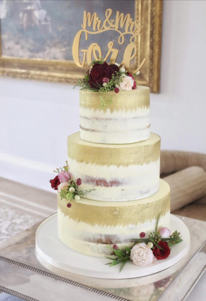 Buttercream wedding cake with gold brush, flowers and topper